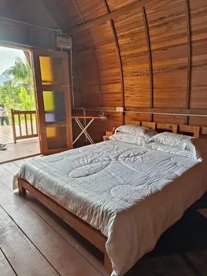 a large bed in a room with a wooden wall at LBA chalet in Balik Pulau