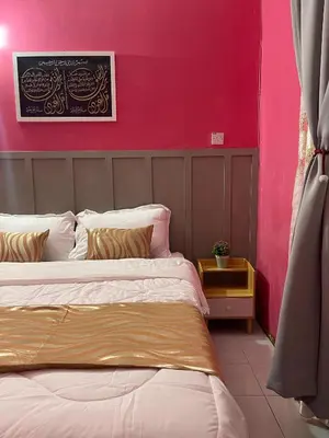 a bedroom with two beds and a pink wall at Venice Raudhah Guest House in Lumut