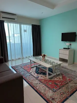 a living room with a coffee table and a television at Laguna Raudhah Apartment in Lumut