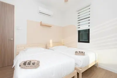 a bedroom with a white bed with two pillows on it at Muji Style 5BR Ferringhi Beach House 15Pax in Batu Ferringhi