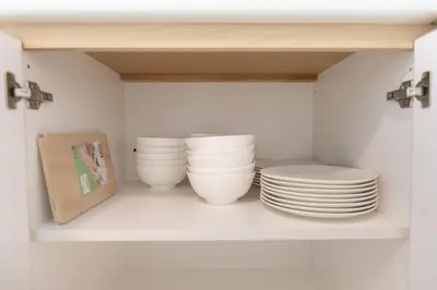 a shelf with plates and bowls in a cabinet at Muji Style 5BR Ferringhi Beach House 15Pax in Batu Ferringhi
