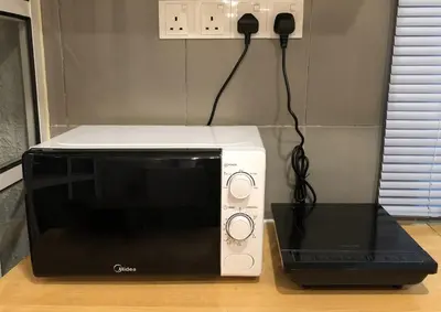 a microwave and a phone on top of a counter at Cozy Suite - Near UTAR - Champs Elysees Kampar in Kampar