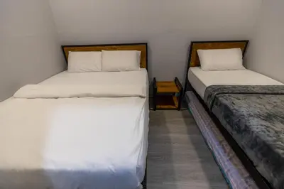 two beds in a small room with white sheets at 5R4B 15Pax V KTV,KID'S POOL,POOL TABLE NEAR USM,LWE HOSPITAL,SPI ARENA in George Town