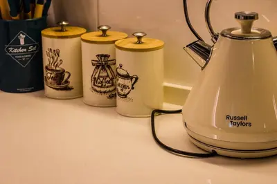 a tea kettle and four cups on a counter at Varnen Cozy Haven - EVCharger in Bukit Mertajam