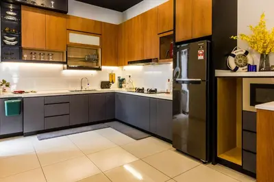 a kitchen with wooden cabinets and a black refrigerator at Varnen Cozy Haven - EVCharger in Bukit Mertajam