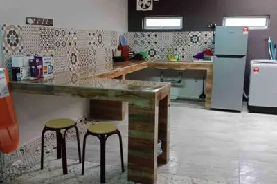 a kitchen with two stools and a counter and a refrigerator at Wi-Fi 100MB Free Ipoh Holiday Suite Taman Anda A5 in Ipoh