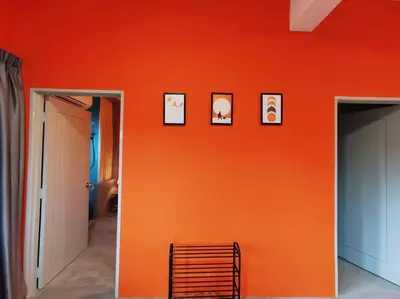 a room with an orange wall with pictures on it at Ipoh town centre - safari 5 pax(2BR) in Ipoh