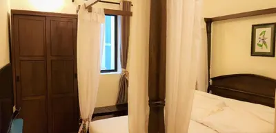 a bedroom with a bed and a wooden cabinet and a window at Betel Nut Lodge in George Town
