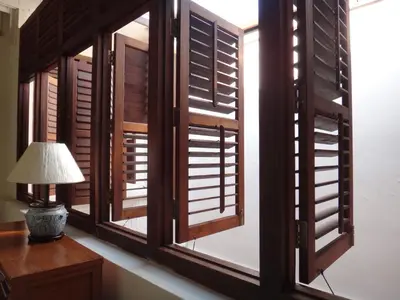 a window with wooden shutters and a lamp on a desk at Betel Nut Lodge in George Town