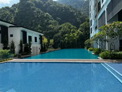 a swimming pool in front of a building with mountains in the background at Ipoh Onsen family suite l Lost World view in Tambun