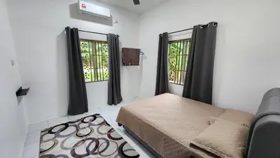a small bedroom with a bed and two windows at Villa Fatima in Sitiawan