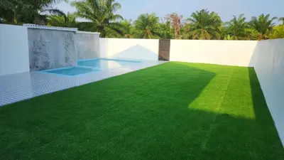 an artificial grass yard in a backyard with a swimming pool at Villa Fatima in Sitiawan