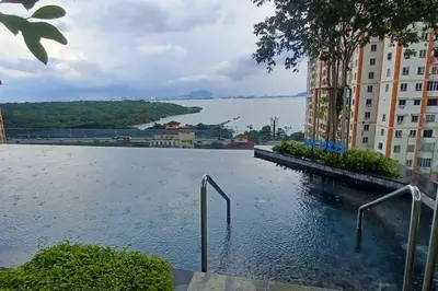 a swimming pool in a building with a view of the water at Stylish Urban Suite Penang - with infinite pool in Jelutong