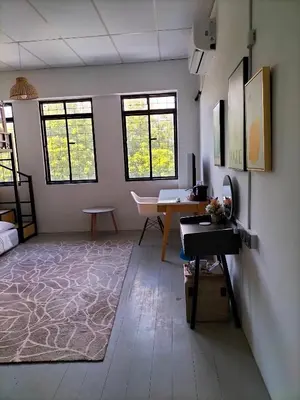 a room with a desk and a table and windows at le melur guest house in George Town