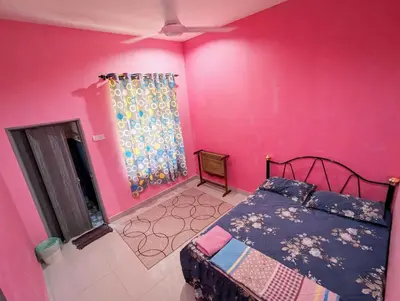 a bedroom with a bed and a pink wall at Aish Homestay in Kuala Lipis