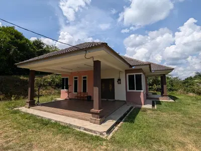 a small house with a deck in a field at Aish Homestay in Kuala Lipis
