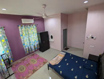 a living room with a bed and a purple wall at Aish Homestay in Kuala Lipis