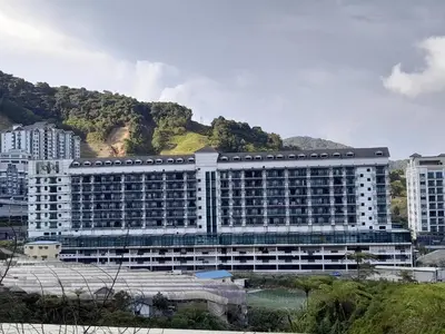 a large white building with a mountain in the background at Cameron Square in Brinchang