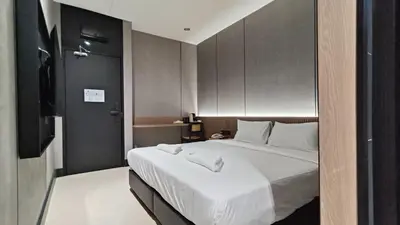 a bedroom with a large bed with white sheets at Urban Inn, Serai Wangi in Padang Serai