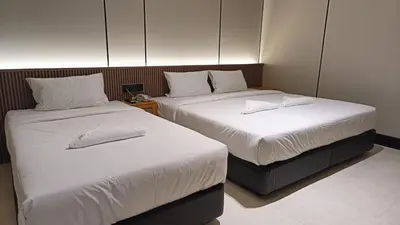 two beds with white sheets and pillows in a room at Urban Inn, Serai Wangi in Padang Serai