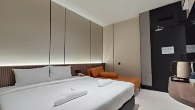 a bedroom with a large white bed and a chair at Urban Inn, Serai Wangi in Padang Serai