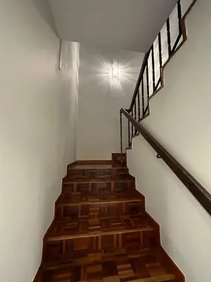 a wooden staircase with a light on the wall at Claire Home Stay in Ipoh