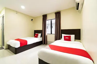 a bedroom with two beds with red and white sheets at OYO 89960 Manjung Inn Hotel in Seri Manjung