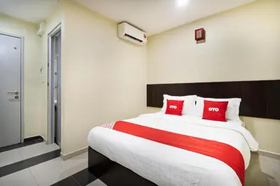 a bedroom with a large bed with red pillows at OYO 89960 Manjung Inn Hotel in Seri Manjung