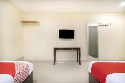 a room with two beds and a desk and a tv at OYO 89960 Manjung Inn Hotel in Seri Manjung