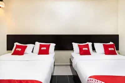 two beds in a room with red and white pillows at OYO 89960 Manjung Inn Hotel in Seri Manjung