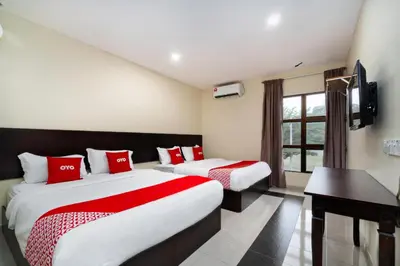 a hotel room with two beds and a flat screen tv at OYO 89960 Manjung Inn Hotel in Seri Manjung
