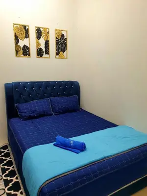a blue bed in a room with two pictures on the wall at LH Alisha Homestay Bandar Utama Gua Musang in Gua Musang