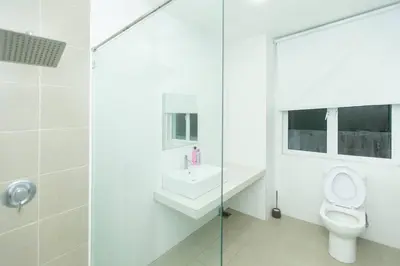a white bathroom with a toilet and a sink at Beach side spacious 5BR 20pax pool house in Batu Ferringhi