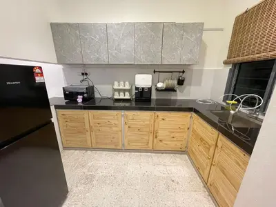 a kitchen with wooden cabinets and a black counter top at TL LEGEND HOMESTAY Ipoh garden east in Ipoh