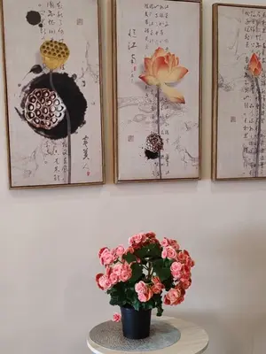a vase with flowers on a table with three pictures at Kensington Sunrise sg, Palas Horizon,kea farm in Brinchang