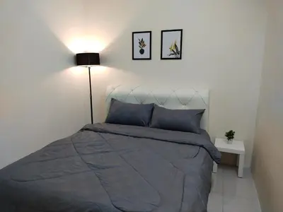 a bedroom with a bed with a blue comforter and a lamp at WAFID HOMESTAY 2 SERI ISKANDAR in Seri Iskandar