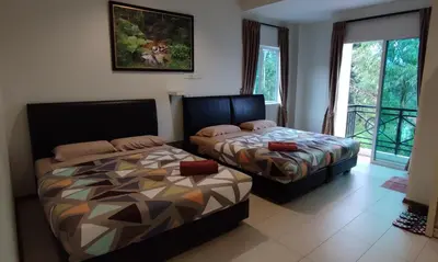 two beds sitting in a room with a window at Rovers Inn Guesthouse - Age 11 And Above Only in Tanah Rata