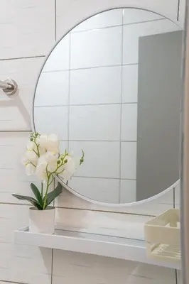 a bathroom with a round mirror and a vase with flowers at Serene Muji Family Cottage(2-7pax) & Sunrise View in Cameron Highlands