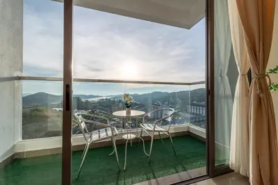 a balcony with a table and chairs in front of a window at Serene Muji Family Cottage(2-7pax) & Sunrise View in Cameron Highlands