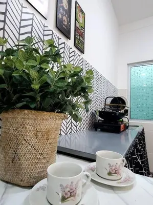 two cups and saucers on a table with a potted plant at Adinda Homestay @ RPB Hospital, Ipoh in Ipoh
