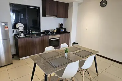 a kitchen with a table with white chairs and a counter at Deluxe Seaview Suite Twin Bed by The Only Bnb in Tanjong Tokong