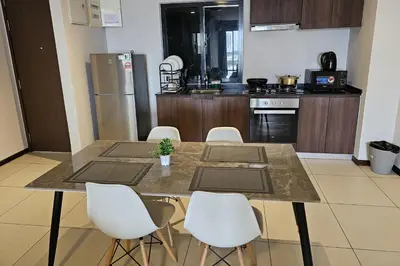 a kitchen with a table with chairs and a refrigerator at Deluxe Seaview Suite Twin Bed by The Only Bnb in Tanjong Tokong