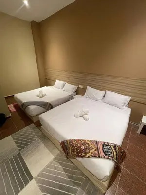 two beds in a hotel room with white sheets at Nahdhoh Hotel in Kubang Semang