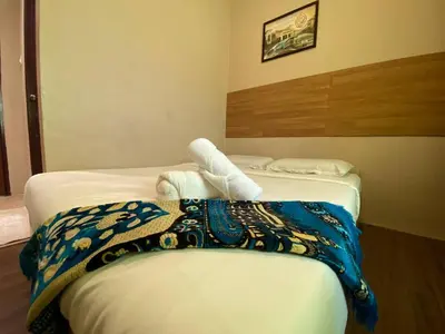 two beds in a hotel room with towels at Nahdhoh Hotel in Kubang Semang