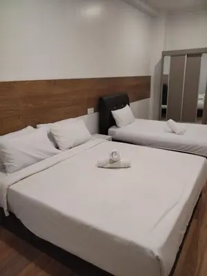 two beds in a room with white sheets and avisor at Nahdhoh Hotel in Kubang Semang