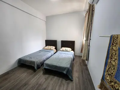 two beds in a room with white walls and wooden floors at Thetamu Homestay مسلم Pesona in Jalan Baharu