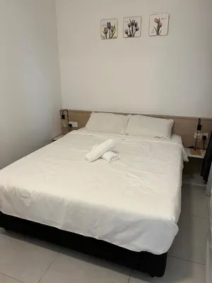 a bedroom with a white bed with two pictures on the wall at Cozy Urban Suites Georgetown View by 3C in Jelutong