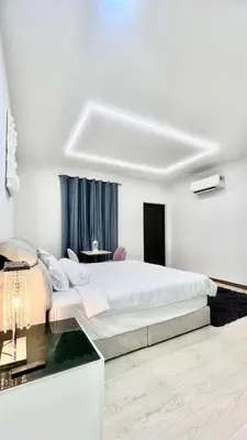 a white bedroom with a large bed and a desk at Three Homestay in Perai