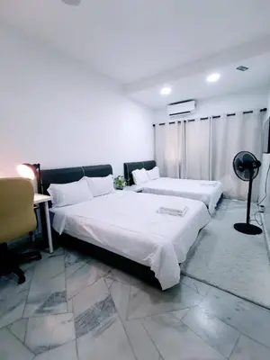 a bedroom with two beds and a desk in it at Three Homestay in Perai