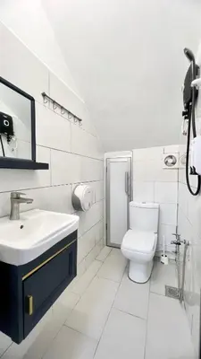 a white bathroom with a sink and a toilet at Three Homestay in Perai
